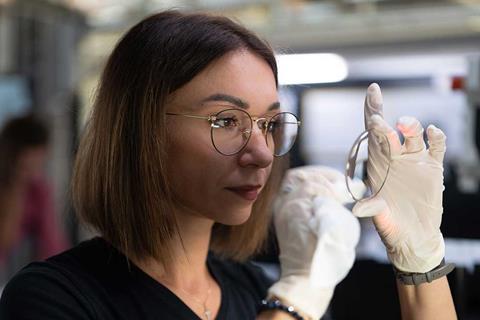 A women inspecting a manufactured lens at Optiswiss